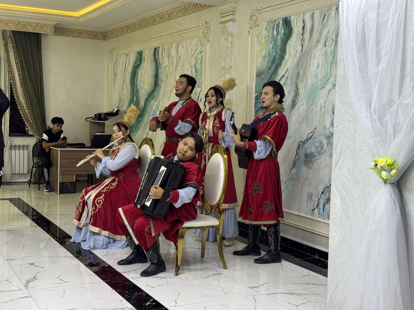 Musicians in red traditional costume playing a flute, guitar and accordion at a celebration