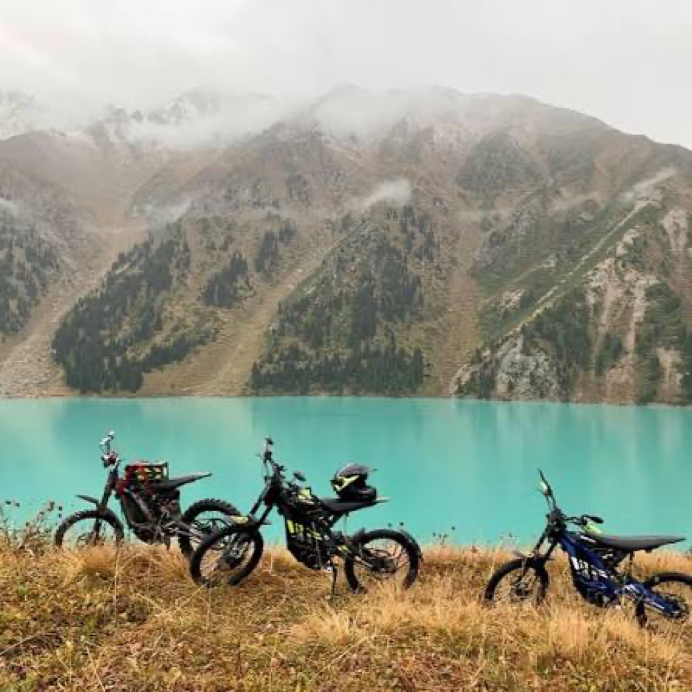 Motorbikes parked beside a turquoise mountain lake