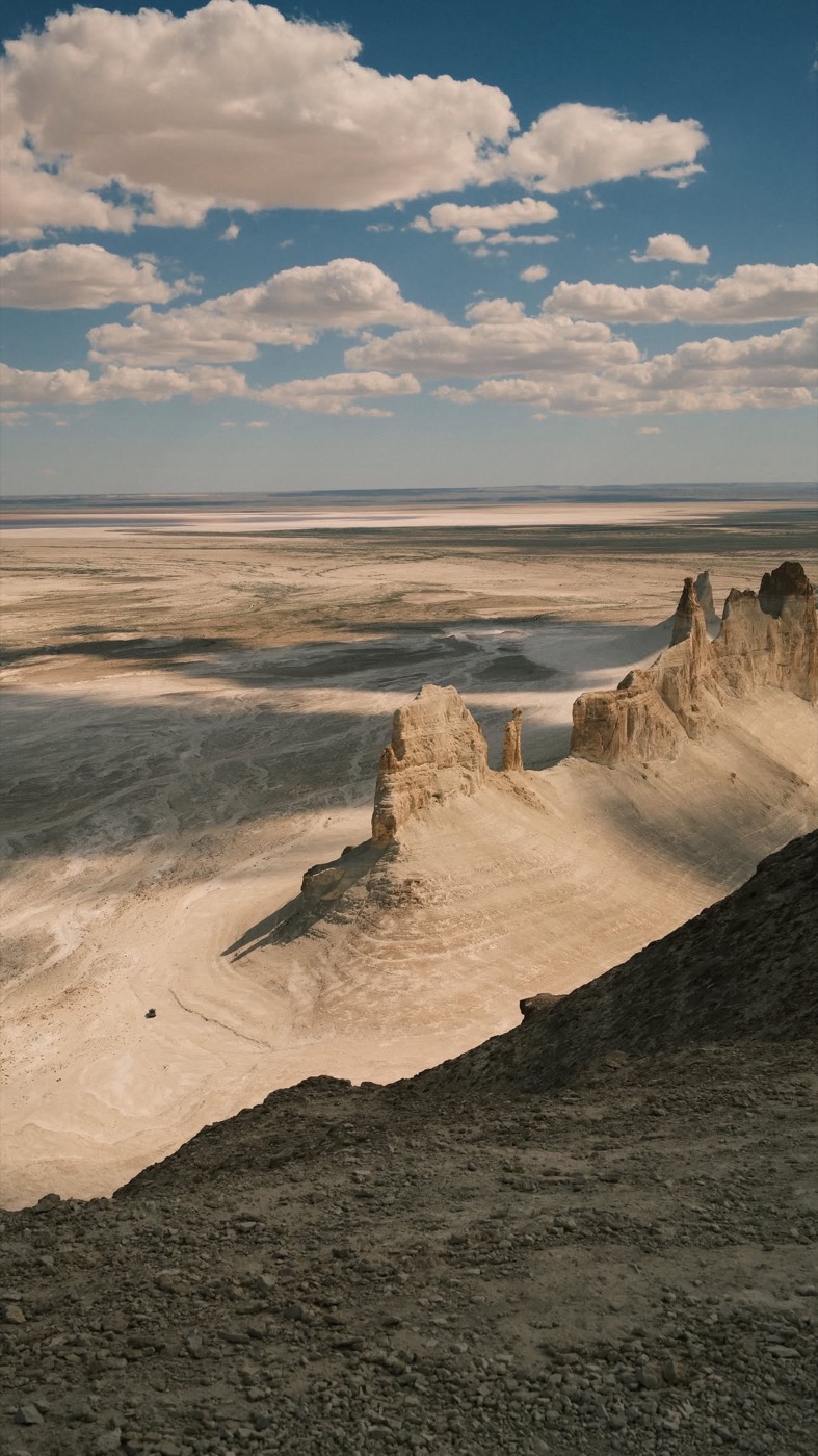 A car on a long desert road in Mangystau, Kazakhstan